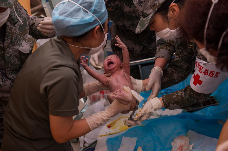 A baby was born in a tent hospital in Lushan County, Sichuan, April 23, 2013. Chen Wei and Yang Yan, parents of the baby, reached the tent hospital and witnessed the birth of their son after three-hour journey by foot, four days after the strong quake. (Xinhua/Chen Cheng)