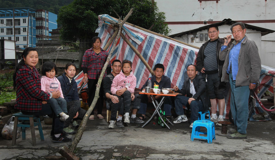 Zhang Zhenghua (center) shares cookware with neighbors in Baoxing County, one of the worst affected areas in the earthquake that jolted Sichuan’s Ya’an City, April 24, 2013. Villagers in the county organized food reserves and available cookware to build temporary kitchens to feed themselves. (Xinhua/Pei Xin)