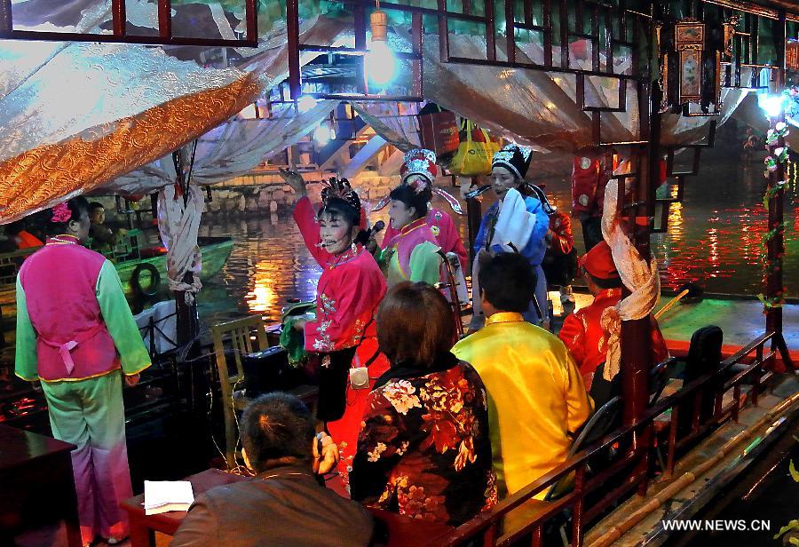 Residents perform Lu Opera, a local opera as well as a national intangible cultural heritage, for tourists on a sightseeing boat in Sanhe Town of Feixi County, east China's Anhui Province, April 24, 2013. The Sanhe Ancient Town, which has a history of more than 2,500 years, is a typical "ancient town full of rivers and lakes, together with small bridges, flowing water and local dwellings." (Xinhua/Wang Song)