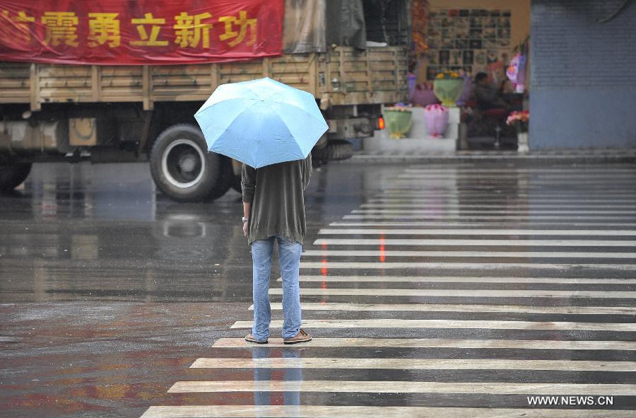 A man waits in rain to cross a crossing near Tingjin Road in Ya'an City, southwest China's Sichuan Province, April 29, 2013. According to China Meteorological Administration, Ya'an is one of the most rainy city in Sichuan in May. Experts remind on secondary disasters in Ya'an, which was hit by a 7.0-magnitude earthquake on April 20, 2013. (Xinhua/Lu Peng)