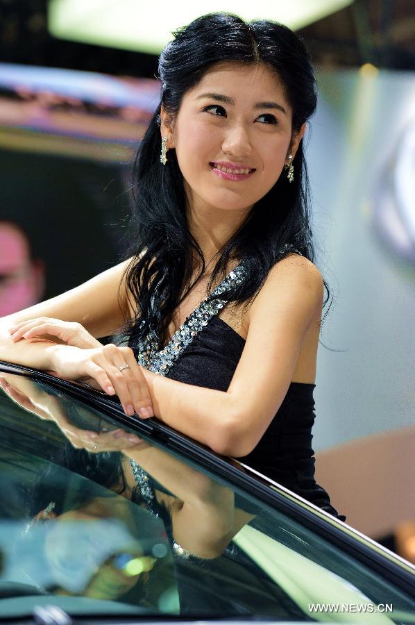 A model poses for photos with a sedan at Fuzhou Auto Fair in Fuzhou, capital of southeast China's Fujian Province, April 29, 2013. (Xinhua/Zhang Guojun)