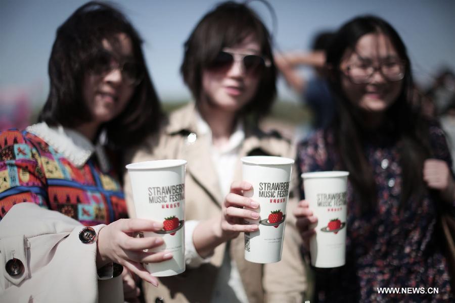 Audiences holding paper cups with the logo of the Strawberry Music Festival pose for a photo during the Strawberry Music Festival in Beijing, capital of China, April 29, 2013. The three-day 2013 Strawberry Music Festival kicked off here on Monday, attracting more than 160 music bands from across the world to perform on stages of eight different styles. (Xinhua/Yao Jianfeng)
