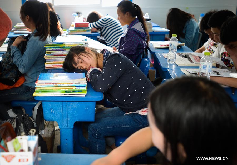 A student has a nap during a break in temporarily-erected classroom at Tianquan Middle School in Tianquan County, southwest China's Sichuan Province, April 29, 2013. The earthquake-hit region in Sichuan Province received a rainfall on April 29, but the rain did not affect those students who have resumed their classes in fabricated houses. (Xinhua/Li Qiaoqiao)