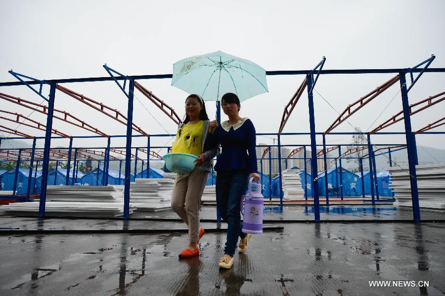 Two students holding an umbrella walk at the campus of Tianquan Middle School in Tianquan County, southwest China's Sichuan Province, April 29, 2013. The earthquake-hit region in Sichuan Province received a rainfall on April 29, but the rain did not affect those students who have resumed their classes in fabricated houses. (Xinhua/Li Qiaoqiao)