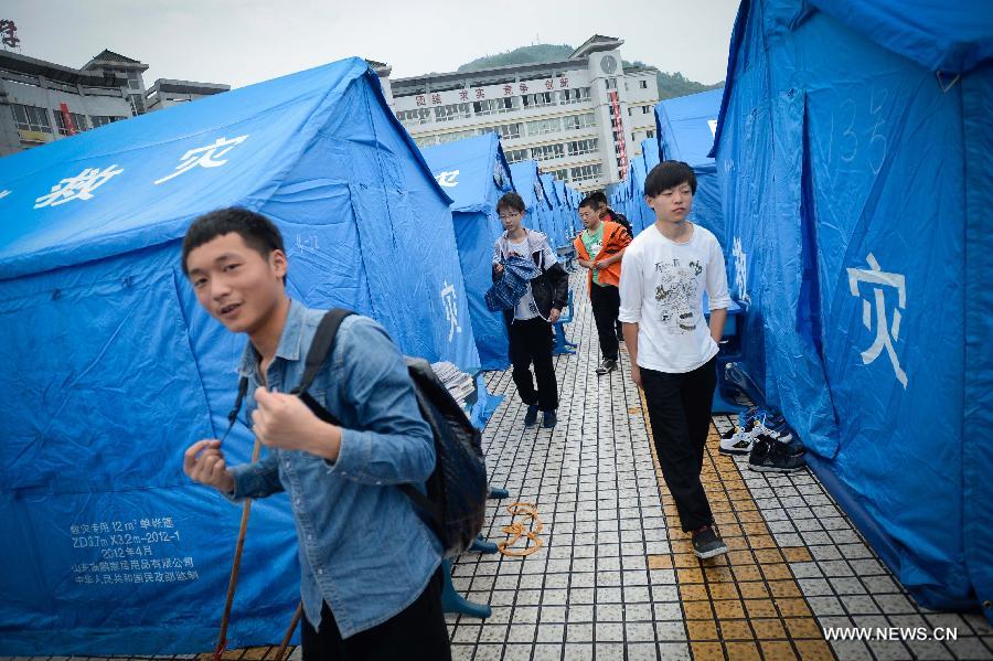Students walk out of their temporarily-erected dormitories to take class in fabricated houses at Tianquan Middle School in Tianquan County, southwest China's Sichuan Province, April 29, 2013. The earthquake-hit region in Sichuan Province received a rainfall on April 29, but the rain did not affect those students who have resumed their classes in fabricated houses. (Xinhua/Li Qiaoqiao) 