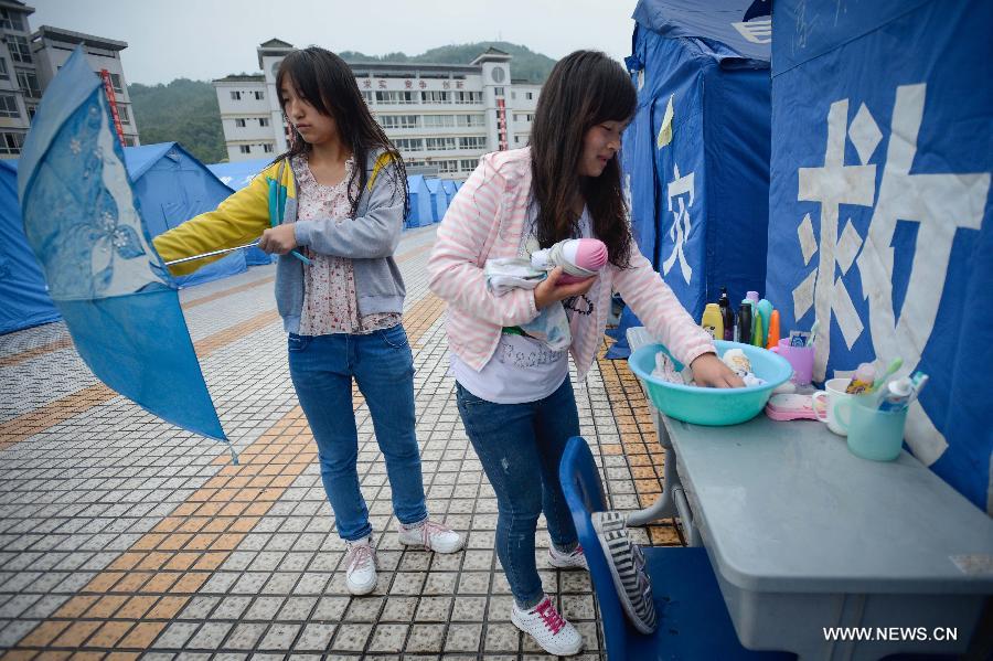Two students arrange their toilet requisites outside their temporarily-erected dormitory at Tianquan Middle School in Tianquan County, southwest China's Sichuan Province, April 29, 2013. The earthquake-hit region in Sichuan Province received a rainfall on April 29, but the rain did not affect those students who have resumed their classes in fabricated houses. (Xinhua/Li Qiaoqiao) 