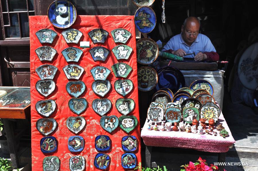 A craftsman engraves patterns onto porcelain pieces in the Zhoucun District of Zibo City in east China's Shandong Province, April 30, 2013. Tourism boosted in Zhoucun during the three-day public holiday celebrating the upcoming international workers' day on May 1. The scenic resort in Zhoucun opened to the public free of charge since March 2011. (Xinhua/Dong Naide)