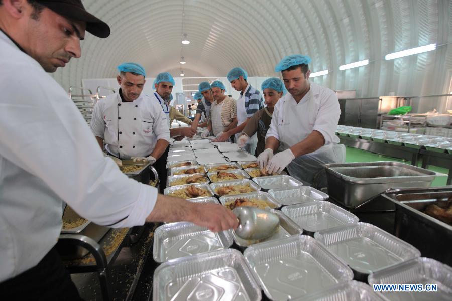 Jordanian chefs and Syrian refugee workers prepare food for distribution to refugees at the Mrajeeb Al Fhood refugee camp, 20 km (12.4 miles) east of the city of Zarqa, April 29, 2013. The Mrajeeb Al Fhood camp, with funding from the United Arab Emirates, has received about 2500 Syrian refugees so far, according to the Red Crescent Society of the United Arab Emirates. (Xinhua/Mohammad Abu Ghosh)