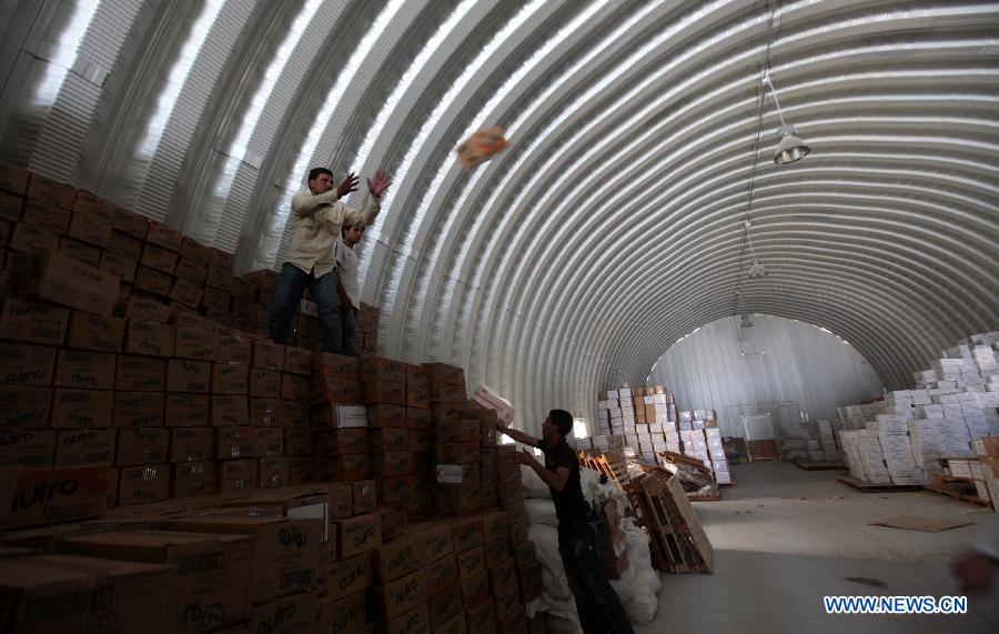 Members of the Red Crescent Society of the United Arab Emirates (UAE) and Syrian refugee workers unload relief materials inside a warehouse at the Mrajeeb Al Fhood refugee camp, 20 km (12.4 miles) east of the city of Zarqa, April 29, 2013. The Mrajeeb Al Fhood camp, with funding from the United Arab Emirates, has received about 2500 Syrian refugees so far, according to the Red Crescent Society of the UAE. (Xinhua/Mohammad Abu Ghosh)