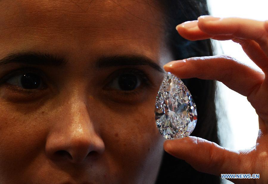 A worker shows the 101.73-carat diamond to the media at the Christie in Geneva, Switzerland, April 30, 2013. Christie will hold spring sale of Jewels auction in Geneva on May 15, 2013. Led by a truly sensational pear-shaped, D colour, flawless diamond of 101.73 carats, the sale will reach to an estimated combined total of 65 million dollars. This Type IIA Flawless gem was found at the Jwaneng mine in Botswana and took 21 months to polish. This gemstone is estimated to be sold at a price between 20 to 30 million dollars and the successful buyer will have the privilege of endowing the diamond a name. (Xinhua/Wang Siwei)