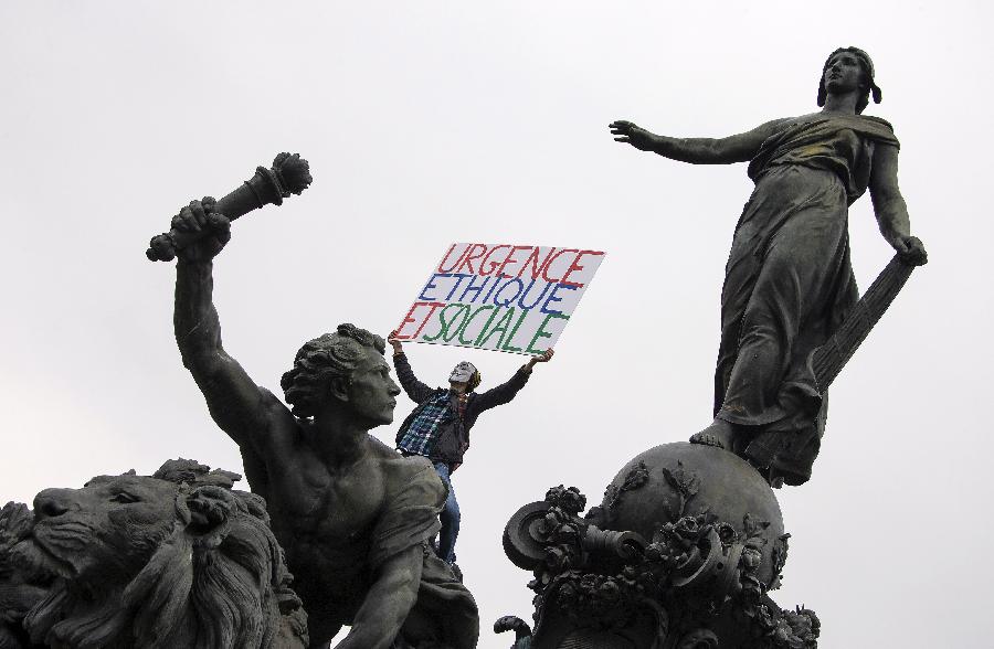 A demonstrator holding a banner on a statue attends the annual May Day demonstration in Paris, France, May 1, 2013. (Xinhua/Etienne Laurent) 