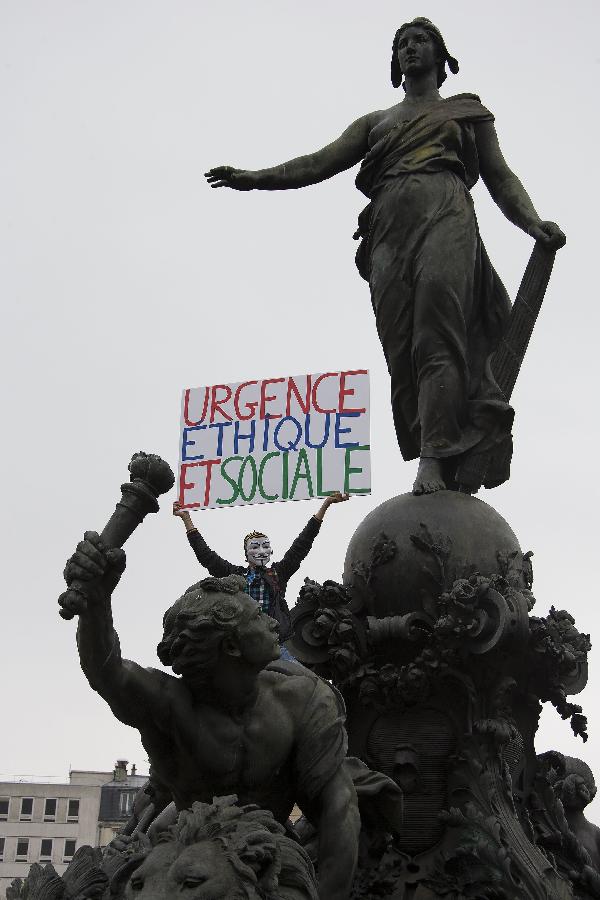 A demonstrator holding a banner on a statue attends the annual May Day demonstration in Paris, France, May 1, 2013. (Xinhua/Etienne Laurent) 