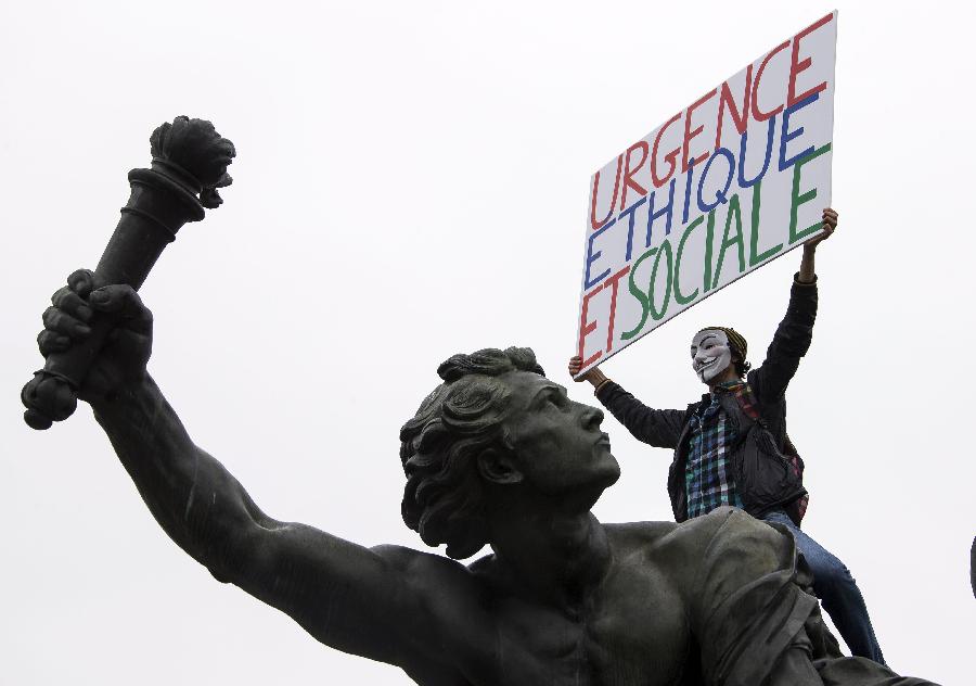 A demonstrator holding a banner on a statue attends the annual May Day demonstration in Paris, France, May 1, 2013. (Xinhua/Etienne Laurent) 
