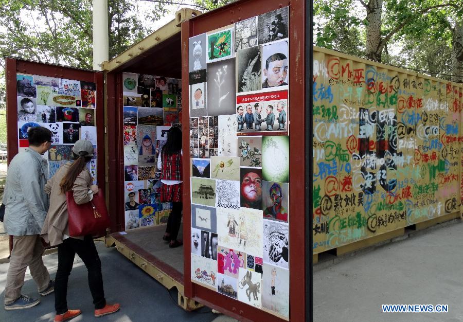Visitors view a mini-exhibition in a container at the Art Beijing 2013 in Beijing, capital of China, May 1, 2013. Opened Wednesday at Agricultural Exhibition Center in Beijing, the annual art fair attracted some 150 participating art organizations. (Xinhua/Li Xin)