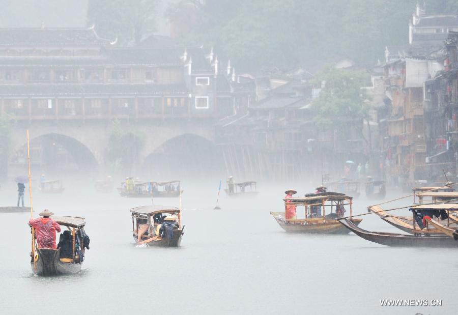 Tourists enjoy the scenery in boats on Tuojiang River by the ancient town of Fenghuang in Fenghuang County of Xiangxi Tu and Miao Autonomous Prefecture, central China's Hunan Province, April 29, 2013. Fenghuang witnessed rainfall on Monday, the first day of the three-day Labor Day holiday. (Xinhua/Zhao Zhongzhi)