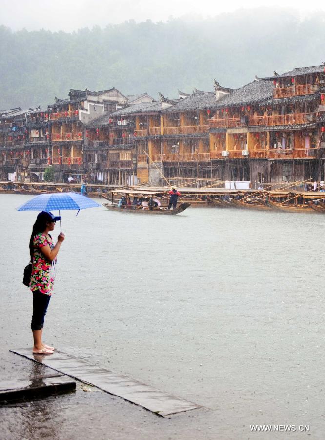 A woman enjoys the scenery by the side of Tuojiang River near the ancient town of Fenghuang in Fenghuang County of Xiangxi Tu and Miao Autonomous Prefecture, central China's Hunan Province, April 29, 2013. Fenghuang witnessed rainfall on Monday, the first day of the three-day Labor Day holiday. (Xinhua/Zhao Zhongzhi)