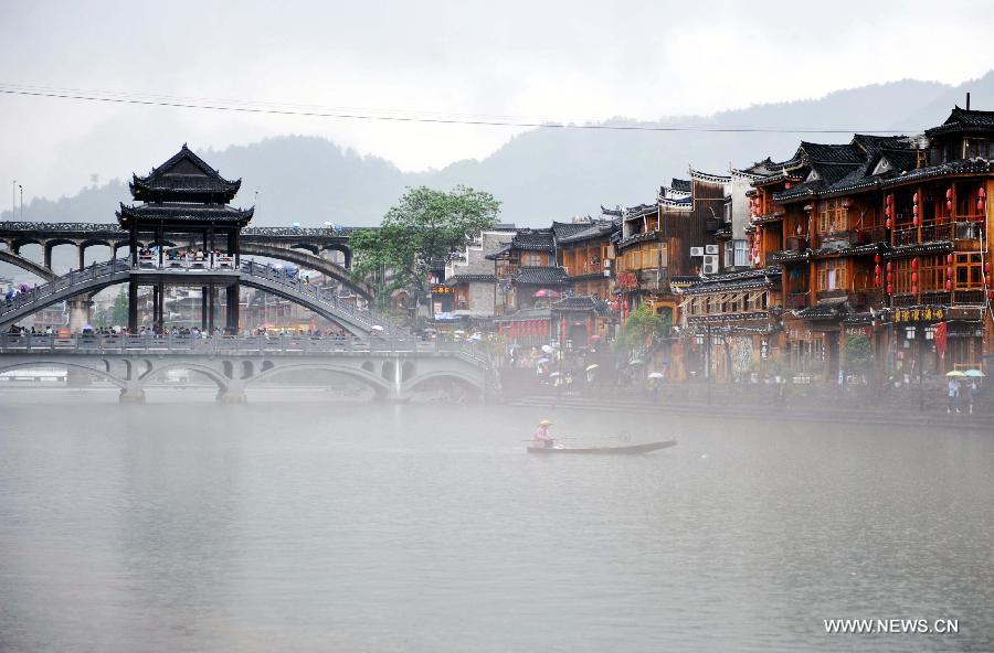 A boat floats in Tuojiang River by the ancient town of Fenghuang in Fenghuang County of Xiangxi Tu and Miao Autonomous Prefecture, central China's Hunan Province, April 29, 2013. Fenghuang witnessed rainfall on Monday, the first day of the three-day Labor Day holiday. (Xinhua/Zhao Zhongzhi)
