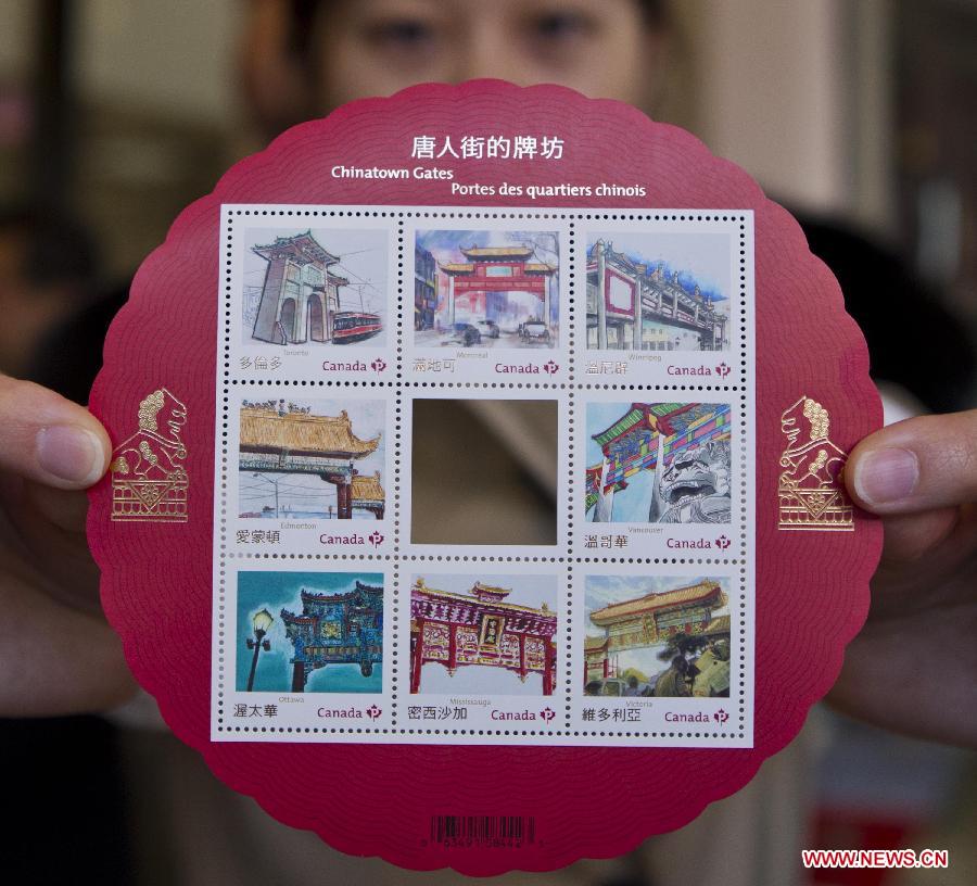A collector shows a souvenir sheet of the Chinatown Gates stamps she bought at a post office in Toronto, Canada, May 1, 2013. Canada Post launched a special series of stamps featuring Chinatown gates located in eight cities across the country on Wednesday to highlight the longstanding heritages of Chinese-Canadians. (Xinhua/Zou Zheng)