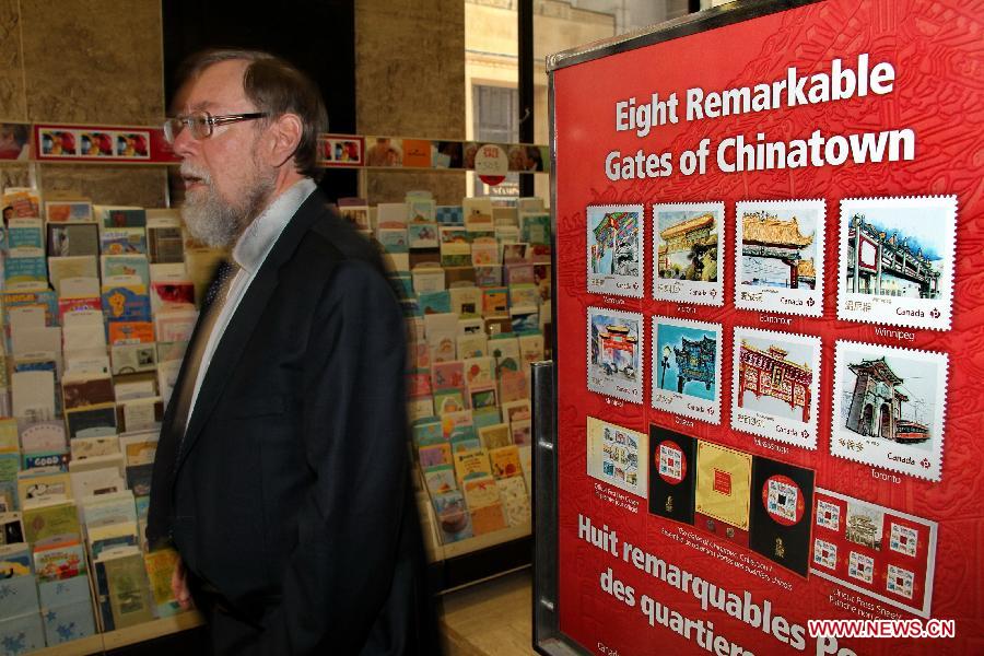 A man walks past the posters of Chinatown Gates stamps in Ottawa, Canada, May 1, 2013. Canada Post launched a special series of stamps featuring Chinatown gates located in eight cities across the country on Wednesday to highlight the longstanding heritages of Chinese-Canadians. (Xinhua/Zhang Dacheng)