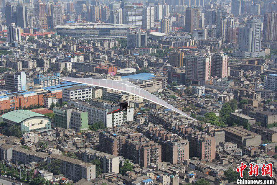 Yang Longfei, an amateur hang glider from Hebei province, soars across the Xiang River in Changsha, Central China's Hunan province, May 1, 2013. After successfully covering a distance of 1,500 meters, Yang became the first person in the world to complete an unpowered flight within a city. (Photo/Chinanews.com)