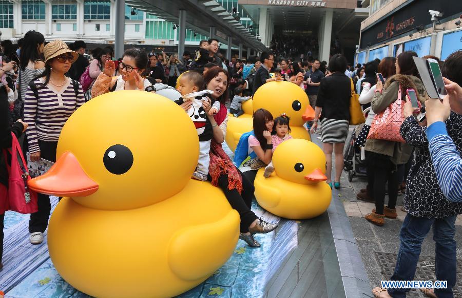 People pose with smaller versions of a huge rubber duck floating on the waters at the Victoria Harbor in Hong Kong, south China, May 2, 2013. The largest rubber duck was created by Dutch artist Florentijn Hofman, with 18 meters of length, 15 meters of width and height. The duck has visited 12 cities since 2007. (Xinhua/Li Peng)