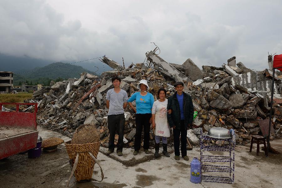 Song Jianwu (1st L) and his family pose for a photo in front of their dismantled house, which was built in 2005 at a cost of some 100,000 yuan (about 16,234 U.S. dollars), at Longmen Township in quake-hit Lushan County, southwest China's Sichuan Province, May 2, 2013. On high alert for secondary disasters, dilapidated houses were dismantled lately after a 7.0-magnitude quake hit Lushan on April 20.(Xinhua/Jin Liangkuai)