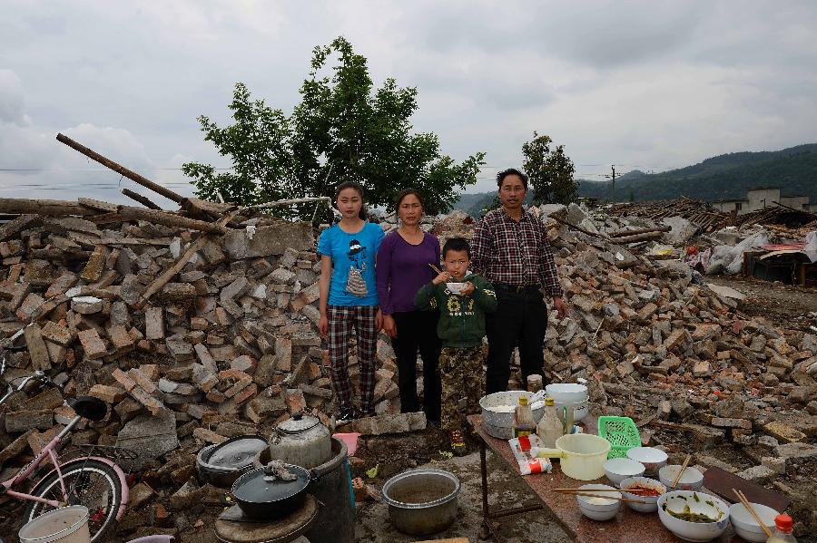 Yang Chenglin (1st R) and his family pose for a photo in front of their dismantled house, which was built in 1998 at a cost of some 100,000 yuan (about 16,234 U.S. dollars), at Longmen Township in quake-hit Lushan County, southwest China's Sichuan Province, May 2, 2013. On high alert for secondary disasters, dilapidated houses were dismantled lately after a 7.0-magnitude quake hit Lushan on April 20.(Xinhua/Jin Liangkuai)