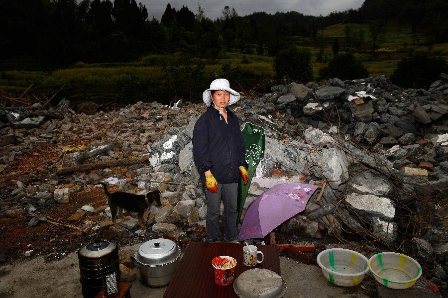 Zhang Mei poses for a photo in front of her dismantled house, which was built in 1995 at a cost of some 30,000 yuan (about 4,870 U.S. dollars), at Longmen Township in quake-hit Lushan County, southwest China's Sichuan Province, May 2, 2013. On high alert for secondary disasters, dilapidated houses were dismantled lately after a 7.0-magnitude quake hit Lushan on April 20.(Xinhua/Jin Liangkuai)
