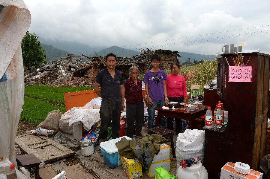 Yang Minghua (1st L) and his family pose for a photo in front of their dismantled house, which was built in 2007 at a cost of some 100,000 yuan (about 16,234 U.S. dollars), at Longmen Township in quake-hit Lushan County, southwest China's Sichuan Province, May 2, 2013. On high alert for secondary disasters, dilapidated houses were dismantled lately after a 7.0-magnitude quake hit Lushan on April 20.(Xinhua/Jin Liangkuai)