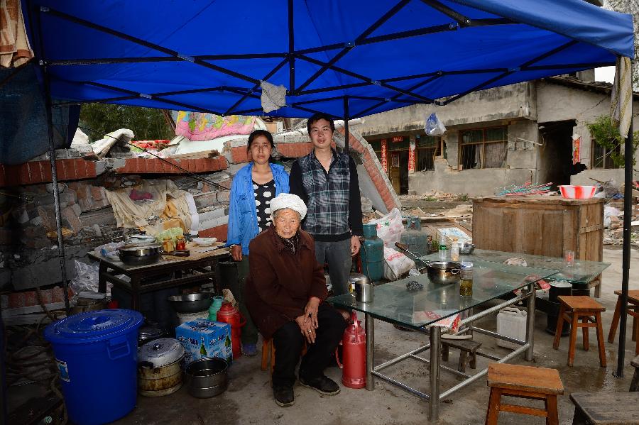 Chen Kangyong and his family pose for a photo in front of their dismantled house, which was built in 2001 at a cost of some 100,000 yuan (about 16,234 U.S. dollars), at Longmen Township in quake-hit Lushan County, southwest China's Sichuan Province, May 2, 2013. On high alert for secondary disasters, dilapidated houses were dismantled lately after a 7.0-magnitude quake hit Lushan on April 20.(Xinhua/Jin Liangkuai)