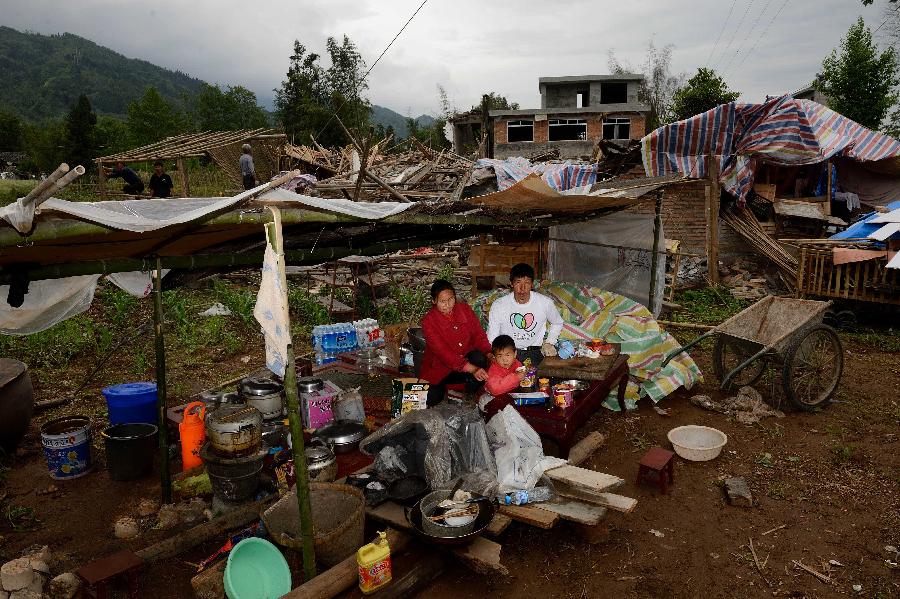 Gao Qingquan (R) and his family pose for a photo in front of their dismantled house, which was built in 2003 at a cost of some 100,000 yuan (about 16,234 U.S. dollars), at Longmen Township in quake-hit Lushan County, southwest China's Sichuan Province, May 2, 2013. On high alert for secondary disasters, dilapidated houses were dismantled lately after a 7.0-magnitude quake hit Lushan on April 20.(Xinhua/Jin Liangkuai)