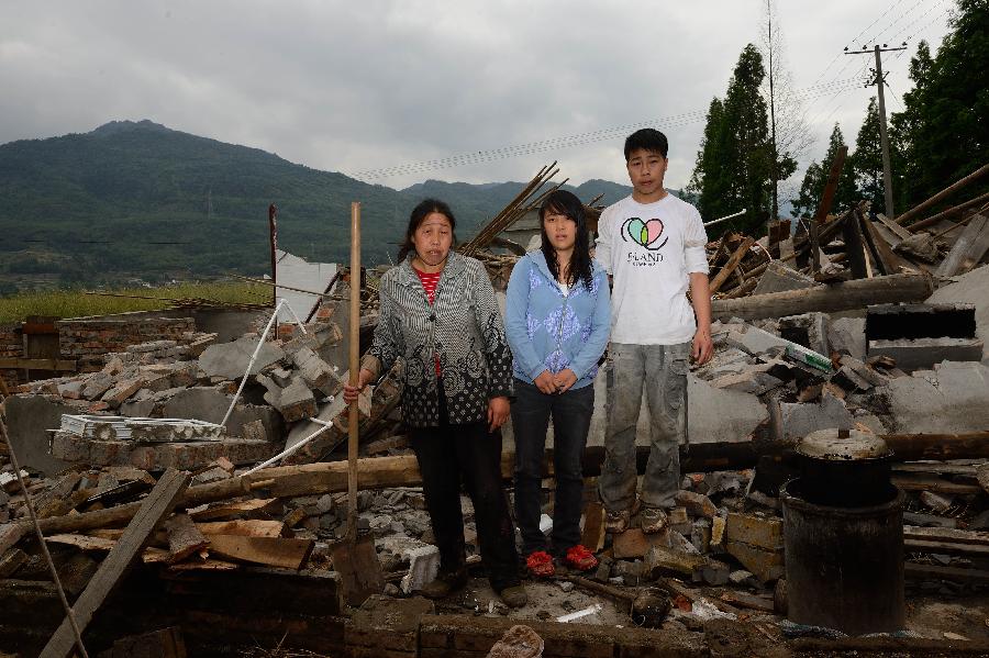 He Kunjiao (R)and his family pose for a photo in front of their dismantled house, which was built in 1997 at a cost of some 50,000 yuan (about 8,117 U.S. dollars), at Longmen Township in quake-hit Lushan County, southwest China's Sichuan Province, May 2, 2013. On high alert for secondary disasters, dilapidated houses were dismantled lately after a 7.0-magnitude quake hit Lushan on April 20.(Xinhua/Jin Liangkuai)