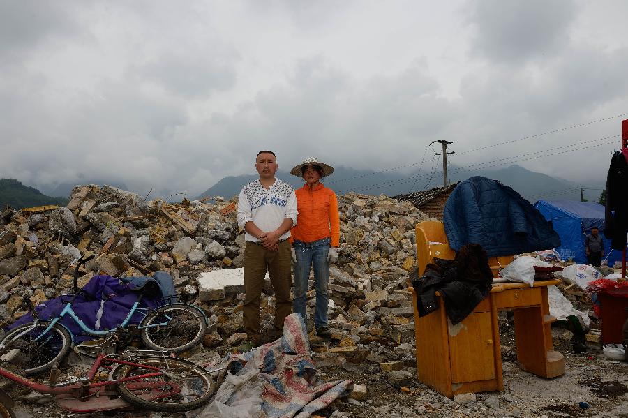 Zhang Huaiqiang and his wife Yang Jiarong pose for a photo in front of their dismantled house, which was built in 2005 at a cost of some 150,000 yuan (about 24,351 U.S. dollars), at Longmen Township in quake-hit Lushan County, southwest China's Sichuan Province, May 2, 2013. On high alert for secondary disasters, dilapidated houses were dismantled lately after a 7.0-magnitude quake hit Lushan on April 20.(Xinhua/Jin Liangkuai)