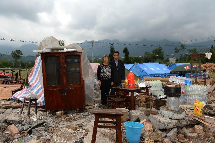 Chen Dingbin and his wife Wang Wenjin pose for a photo in front of their dismantled house, which was built in 1999 at a cost of some 40,000 yuan (about 6,494 U.S. dollars), at Longmen Township in quake-hit Lushan County, southwest China's Sichuan Province, May 2, 2013. On high alert for secondary disasters, dilapidated houses were dismantled lately after a 7.0-magnitude quake hit Lushan on April 20.(Xinhua/Jin Liangkuai)