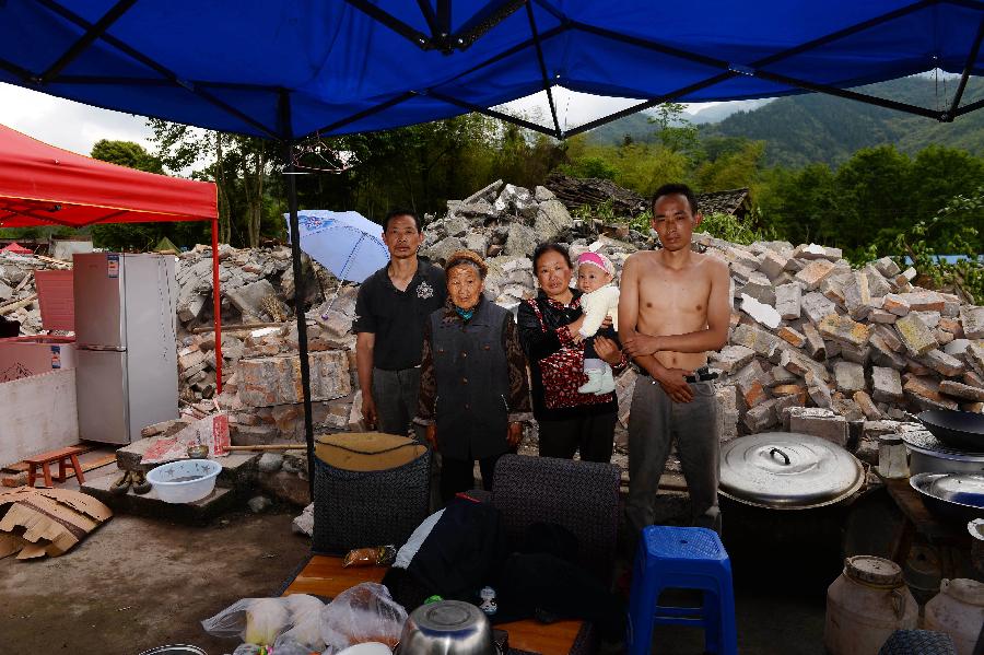 Huang Wanyun (1st L) and his family pose for a photo in front of their dismantled house, which was built in 1998 at a cost of some 120,000 yuan (about 19,481 U.S. dollars), at Longmen Township in quake-hit Lushan County, southwest China's Sichuan Province, May 2, 2013. On high alert for secondary disasters, dilapidated houses were dismantled lately after a 7.0-magnitude quake hit Lushan on April 20.(Xinhua/Jin Liangkuai)