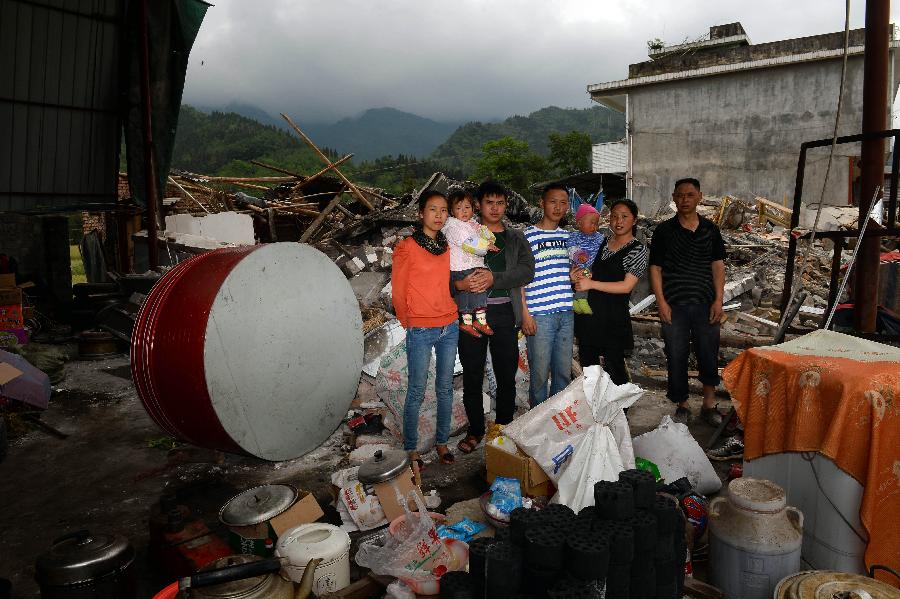 Gao Yongwen (1st R) and his family pose for a photo in front of their dismantled house, where they have lived for more than 20 years, at Longmen Township in quake-hit Lushan County, southwest China's Sichuan Province, May 2, 2013. On high alert for secondary disasters, dilapidated houses were dismantled lately after a 7.0-magnitude quake hit Lushan on April 20.(Xinhua/Jin Liangkuai)
