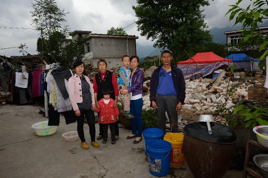 Yang Mingsheng (1st R) and his family pose for a photo in front of their dismantled house, where they have lived for more than 30 years, at Longmen Township in quake-hit Lushan County, southwest China's Sichuan Province, May 2, 2013. On high alert for secondary disasters, dilapidated houses were dismantled lately after a 7.0-magnitude quake hit Lushan on April 20.(Xinhua/Jin Liangkuai)