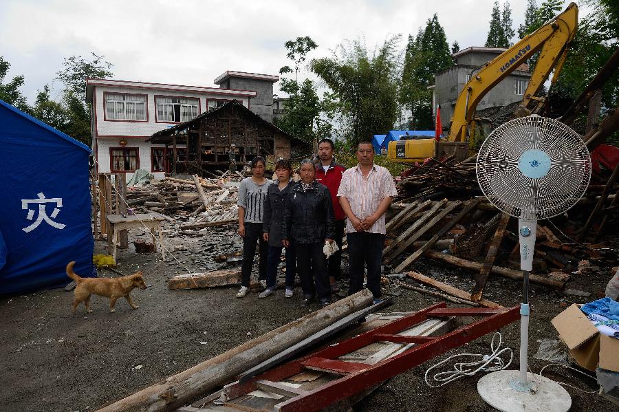 Zhang Xiaohua (1st R) and his family pose for a photo in front of their dismantled house, where they have lived for more than 20 years, at Longmen Township in quake-hit Lushan County, southwest China's Sichuan Province, May 2, 2013. On high alert for secondary disasters, dilapidated houses were dismantled lately after a 7.0-magnitude quake hit Lushan on April 20.(Xinhua/Jin Liangkuai)