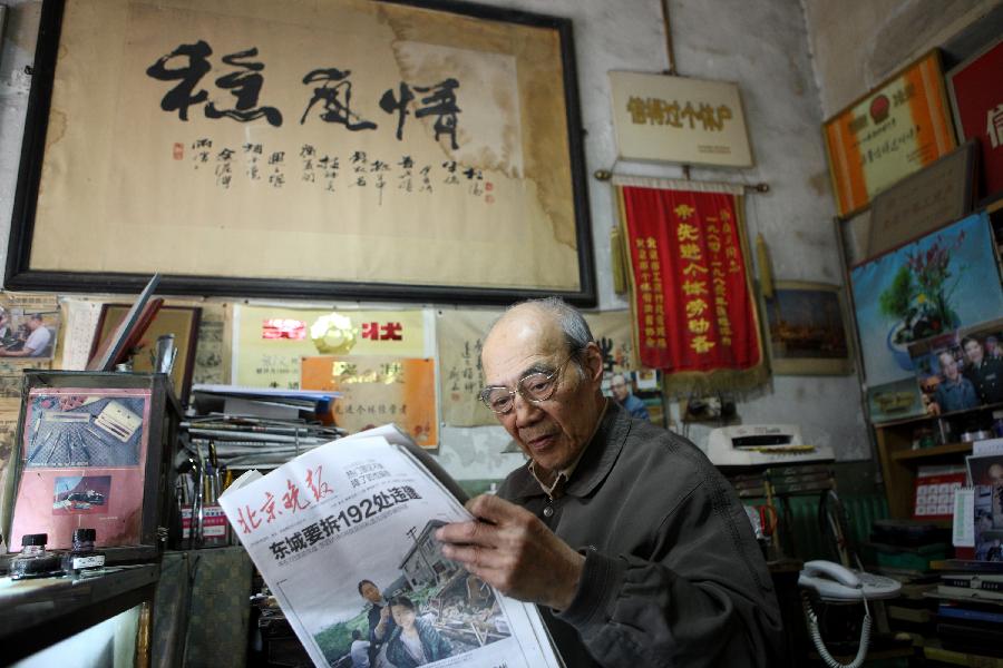 Zhang Guangyi reads Beijing Evening News at his shop in Beijing, capital of China, April 26, 2013.  (Xinhua/Xu Zijian)