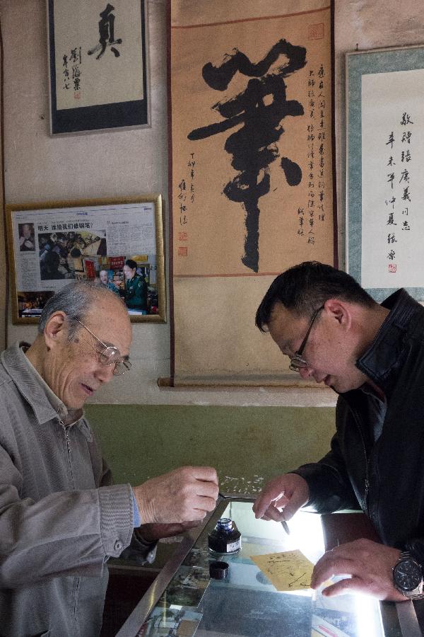 A customer Yue Guozhong (R) buys a pen from Zhang Guangyi at Zhang's shop in Beijing, capital of China, April 24, 2013.  (Xinhua/Xu Zijian)