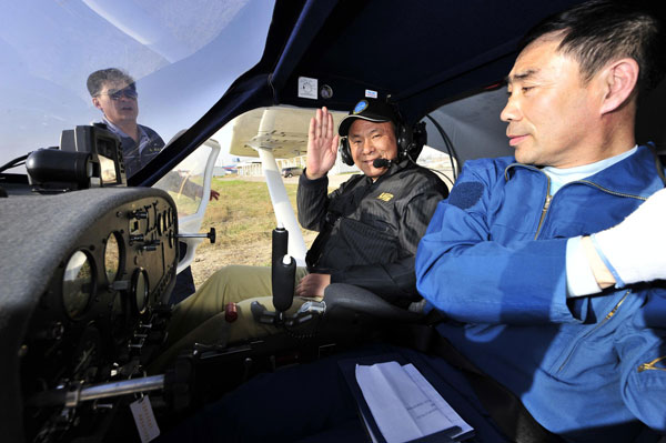 Luo Yi, an aviation expert, waves as he boards an aircraft in Huanghua, North China’s Hebei province, on April 30, 2013. During the May Day holiday, over 30 flying fans of various backgrounds and all with years of computer simulated flying experience came to Huanghua and experienced the real thing organized by an online forum of military fans.[Photo/Xinhua] 