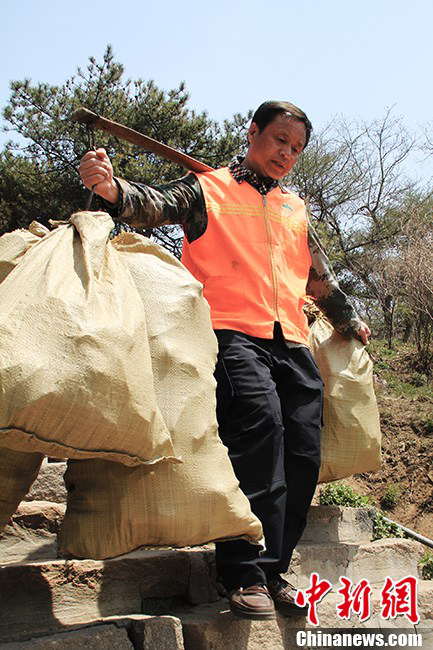 At 5 p.m., Zhang goes down the mountain with six bags of garbage on his shoulders. Zhang said that there were fewer visitors than two days ago and he could call it a day earlier. (Photo by Li Xianglei/ Chinanews.com)