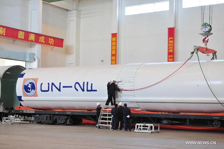 Workers try to install slings on the first stage launcher of the Long March 2-F rocket which will carry China's new manned spacecraft Shenzhou-10 at the Jiuquan Satellite Launch Center for further test in Jiuquan, northwest China's Gansu Province, May 3, 2013. The Long March 2-F rocket was delivered to the center on May 2 and it is technologically advanced and more reliable compared to the one that carried the Shenzhou-9. Shenzhou-10, scheduled to blast off early next month, was delivered to the launch center in northwest China on March 31. (Xinhua/Liang Jie) 