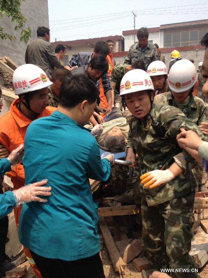 Rescuers carry a survivor at the site where a two-story building collapsed in Hedao village, Fengzhuang township in Yanjin County, central China's Henan Province, May 3, 2013. The building collapsed on Friday morning, leaving at least seven workers dead. Thirty-seven people, most of them women, were lifting the building's foundations when it toppled. Twenty-one people have been rescued from the collapsed building. Rescue efforts are continuing. (Xinhua/Li Zhi)
