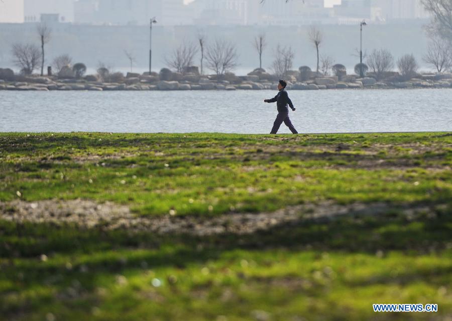 A woman walks along the lake bank of the Nanhu Park in Changchun, capital of northeast China's Jilin Province, May 5, 2013. Sunday is the beginning of the 7th solar term in Chinese lunar calendar, which indicates the coming of summer. The temperature in Jilin rebounded in recent days. (Xinhua/Zhang Nan)