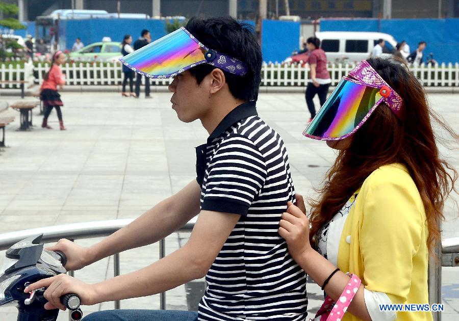 People with sunhats are seen riding in Zhengzhou, capital of central China's Henan Province, May 5, 2013. Sunday is the beginning of the 7th solar term in Chinese lunar calendar, which indicates the coming of summer. The temperature in Henan rebounded in recent days. (Xinhua/Wang Song)