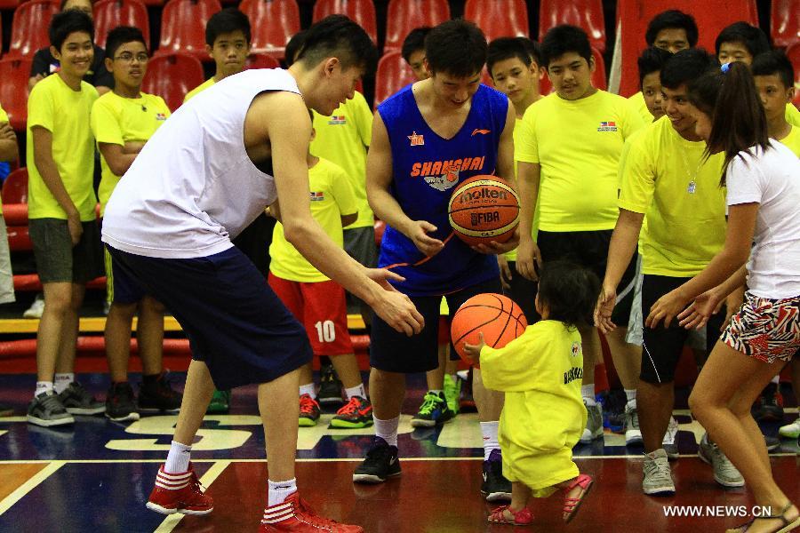 Players from the Shanghai Sharks play basketball with a Filipine girl during a basketball clinic in Pasig City, the Philippines, May 5, 2013. Yao and his Shanghai Sharks are in Manila on a friendly visit. They will attend two exhibition games respectively with the Smart Gilas Team and the Philippine Basketball Association (PBA) Selection. (Xinhua/Rouelle Umali)