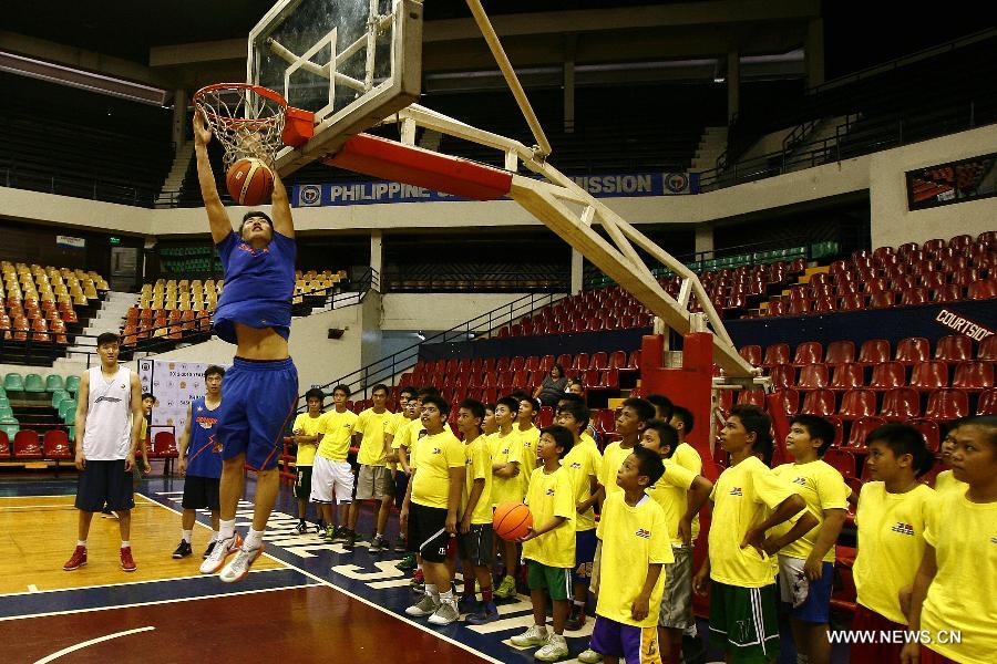 A player from the Shanghai Sharks dunks as Filipine boys watch during a basketball clinic in Pasig City, the Philippines, May 5, 2013. Yao and his Shanghai Sharks are in Manila on a friendly visit. They will attend two exhibition games respectively with the Smart Gilas Team and the Philippine Basketball Association (PBA) Selection. (Xinhua/Rouelle Umali)