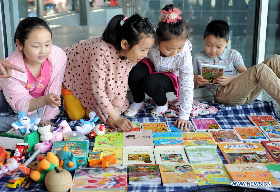 Pupils sell their secondhand books at the secondhand book fair in Nanjing, capital of east China's Jiangsu Province, May 5, 2013. During the fair, pupils and middle school students could sell or exchange their idle books, stationery and toys as well, by which they were expected by the organizer to learn a frugal lifestyle. (Xinhua/Sun Can)