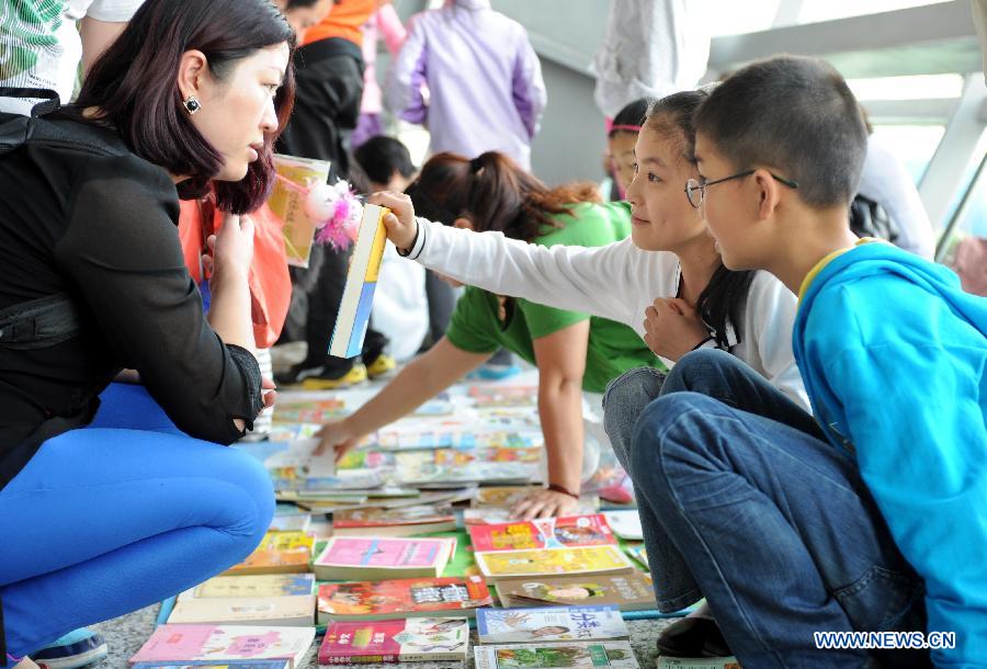 A girl tries to sell a book to a mother at the secondhand book fair in Nanjing, capital of east China's Jiangsu Province, May 5, 2013. During the fair, pupils and middle school students could sell or exchange their idle books, stationery and toys as well, by which they were expected by the organizer to learn a frugal lifestyle. (Xinhua/Sun Can)